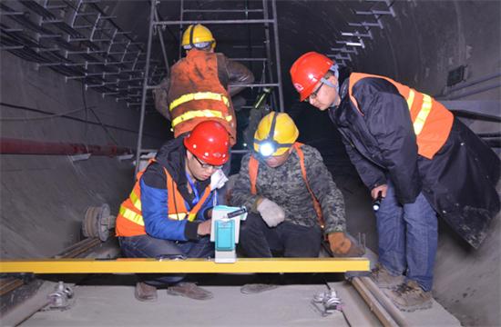 隨著我國公路建設規(guī)模的日益擴大，公路隧道建設取得了很大的發(fā)展,公路隧道具有斷面大，地質(zhì)條件和施工技術復雜等特點，加之設計時對地質(zhì)條件的認識不夠全面準確，通車后存在的隧道老化、運營管理和維護等方面的原因，致使我國公路隧道的病害問題十分嚴重，隧道襯砌背后的空洞問題就是其一，由此引起的拱頂上鼓及襯砌內(nèi)緣壓裂、掉塊的現(xiàn)象嚴重影響到公路隧道的使用壽命。因此加強對隧道襯砌背后空洞的檢測判斷和處理，是隧道工程病害處理的重要一環(huán)。 一、檢查目的和必要性 目的：隧道拱部襯砌出現(xiàn)空洞剝落掉塊直接危及行車安全，但襯砌內(nèi)部病害隱蔽，無法通過肉眼發(fā)現(xiàn)，通過人工敲擊可有效發(fā)現(xiàn)襯砌內(nèi)部空洞等隱患，并對無損檢測資料有針對性的進行驗證。 必要性：通過隧道找部襯砌人工敲擊檢查。可對大部分拱部病害及早發(fā)現(xiàn)并進行整治，從而降低運營期間拱部襯砌剝落掉塊的風險。 二、檢查時機和范圍 1、檢查時機 隧道二次襯砌貫通后，接觸網(wǎng)安裝前為最佳檢查時機，接觸網(wǎng)安裝后通電前次之，通電后則須停電 。 2、接觸網(wǎng)安裝前、后敲擊檢查的區(qū)別 接觸網(wǎng)安裝前后，敲擊方法、車輛、工具基本相同。主要區(qū)別： （1）接觸網(wǎng)作業(yè)車檢查平臺，升起高度或檢查架搭設高度不同，接觸網(wǎng)安裝前接觸網(wǎng)作業(yè)車檢查平臺升起高度或檢查架搭設高度距拱頂3米左右，拱頂至拱腰均易于敲擊，接觸網(wǎng)安裝后接觸網(wǎng)作業(yè)車檢查平臺升起高度，或檢查架搭設高度距離拱頂至少4米。 （2）檢查槌長度不同。接觸網(wǎng)安裝前檢查槌長度為2米左右，接觸網(wǎng)安裝后檢查槌長度為2.5米至4.6米。 3、檢查范圍 當使用供電檢查車或軌道車平板上搭檢查架檢查時，從拱頂中心線至起拱線半幅為一次敲擊檢查范圍，當使用檢查架檢查時，從線路左側(cè)起拱線至線路右側(cè)起拱線全幅為一次敲擊檢查范圍。 圖片描述(最多50字) 三、檢查前準備工作 1、車輛：接觸網(wǎng)檢查車，平板車搭檢查架，在鋼軌或側(cè)溝蓋板上推進檢查架，以雙線隧道，軌頂至拱頂9米為例，且檢查平臺距接觸網(wǎng)立柱等侵限物體保持10至20厘米間距。 （1）采用接觸網(wǎng)檢查車檢查無接觸網(wǎng)時，檢查平臺高度以距拱頂3米為宜，檢查平臺橫向放置，有接觸網(wǎng)時，檢查平臺高度以距拱頂5米為宜，檢查平臺縱向放置，需要時再旋轉(zhuǎn)到橫向位置。 （2）平板車搭檢查架，鋼軌上安裝檢查架或側(cè)向水溝蓋板和兩線間底板頂搭設檢查架，無接觸網(wǎng)時，檢查平臺高度以距拱頂距離3米為宜，檢查平臺橫向?qū)挾瓤蛇_9米，有接觸網(wǎng)時，檢查平臺高度距離拱頂4米為宜，兩線間平臺需下凹0.5米，檢查平臺橫向?qū)挾瓤蛇_9.5米。 圖片描述(最多50字) 2、工具：大型工具有：接觸網(wǎng)檢查車、軌道車（含平板車）、檢查架（根據(jù)凈空定制）；小型工具有：手提式強光手電筒、頭部礦燈、檢查槌（空心鋼管直徑30mm，一端焊接一根尖頭鋼筋一端焊接一根平頭鋼筋，長度2至4.6米不等），卷尺、塞尺、鋼直尺、噴漆、桶裝油漆、漆桿（4.5米長竹竿一端綁扎油漆刷）、檢查梯、對講機、照相機、手套、安全帶、安全帽、防護衣、護目鏡、口罩、記錄本、黑水筆等。 3、人員：作業(yè)小組由8人組成（使用接觸網(wǎng)檢查車或軌道車時需1人持對講機指揮車輛），檢查車分工為：3人持檢查槌（敲擊半幅拱頂線路正上方拱腰，線路側(cè)方拱腰至起拱線），2人聽敲擊音并標記，1人記錄并拍照，1人指揮并負責安全檢查和提示，檢查架分工為：4人持檢查槌敲擊拱頂、拱腰，2人聽敲擊音標記并負責指揮及安全檢查提示，2人記錄并拍照。 四、敲擊檢查程序 1、開窗安排：提前一天申請檢查天窗，天窗時間本線封鎖不少于8小時，鄰線限速每小時20公里，根據(jù)批準的天窗計劃，駐站聯(lián)絡員在《行車設備登記簿》內(nèi)登記，列車高度員下達調(diào)度命令；施工負責人接到調(diào)度命令后按調(diào)度命令憑證發(fā)車；檢查車到指定地點后，立即設置防護體系。在距離檢查地點20米處現(xiàn)場防護員設置移動停車信號彈（燈），在距離施工地點800米兩端防護員設置顯示停車手信號；鄰線防護需設置移動減速信號牌和減速地點標。天窗作業(yè)計劃結(jié)束前機車返回申請?？奎c。駐站聯(lián)絡員與現(xiàn)場防護員在執(zhí)行防護任務時，應佩戴標志攜帶通信設備，現(xiàn)場防護員還應攜帶必要的防護用品；隨時掌握現(xiàn)場和列車運行情況。發(fā)現(xiàn)異常情況及時通知車站值班員和施工負責人。駐站聯(lián)絡員應與現(xiàn)場防護員時刻保持聯(lián)系。 圖片描述(最多50字) 2、敲擊作業(yè)：車輛行駛速度控制在每小時5公里以內(nèi)，檢查架推進速度控制在每小時1公里以內(nèi)，行進過程中進行敲擊，憑敲擊聲音辨別是否存在空洞，聲音異常時停車仔細敲擊確認空洞范圍，施工縫、混凝土修補、蜂窩、混凝土表面有雜物（如鋼筋頭、注漿管等）、施工冷縫、止水帶外露、防水板外露、閉環(huán)裂紋、變形外鼓等重點處所均停車進行仔細敲擊檢查。 3、照明配置、照度、范圍：BAD305手提式防爆探照燈2臺，BAD212微型手持防爆調(diào)光工作燈2臺，LED722B充電頭燈2臺，照度不低于250勒克斯，照明可視距度10m。 4、敲擊人員自我防護注意事項：（1）作業(yè)前將勞動防護用品穿戴整齊‘（2）攀爬腳手架時，要站穩(wěn)扶牢。登上檢查平臺后，須首先掛好安全帶和安裝欄桿扶手，工具應放置穩(wěn)固。（3）接觸網(wǎng)檢查車檢查平臺、檢查架移動前應通知作業(yè)人員停止作業(yè)，將工具擺放穩(wěn)固，人員蹲下扶牢，目視前進方向，機車指揮人員發(fā)現(xiàn)侵限物體要及時停車，拆除侵限物體。檢查架移動就位后，必須設好滾輪制動和斜撐后，方可作業(yè)。（4）檢查小組人員必須團結(jié)協(xié)作、聽從指揮，相互提醒安全注意事項，做到自控、互控。（5）人員站位要相對固定，避免檢查槌等工具碰傷人員。（6）清除襯砌掉塊時，應高聲提醒所有人員注意安全，下方無人時，方可進行作業(yè)。（7）鄰線來車時，須停止作業(yè)，小穩(wěn)扶牢，檢查工具不得侵限。 5、檢查架的組成：同槽鋼跑道、腳手架滾輪及抽動裝置、 鋼管立柱、鋼管橫撐、鋼管斜撐、十字卡、萬向卡、腳手板及鐵絲、欄桿及鎖口鋼筋、反光標等組成。 6、缺陷確認：敲擊聲音清脆，發(fā)出“鐺、鐺、鐺”的聲音說明襯砌混凝土比較密實，如果敲擊聲音沉悶出現(xiàn)“咚、咚、咚”的聲音，說明襯砌混凝土存在空洞，附帶檢查內(nèi)容包括襯砌掉塊、裂紋、滲漏水、露筋、鋼筋保護層厚度不足、蜂窩麻面、混凝土夾帶雜物等。 7、問題標記：發(fā)現(xiàn)問題停車采用紅油漆標記問題范圍，測量（估算）相關尺寸，將病害類型、尺寸等數(shù)據(jù)詳細記錄、拍照存檔，如在空洞外邊界標記面積范圍，在裂縫起終點位置用箭頭（箭頭朝向裂紋處）標記長度，箭頭旁標出裂紋寬度值，同時將問題類型、編號、里程用紅油漆在問題位置邊墻上進行標記，以便日后整改。標記形式“BLWKD-1-K493+179”，BLW指白力塢隧道，KD指拱部空洞，1指編號為1號，K493+179指空洞里程，若一個隧道有多處空洞，序號按里程從小到大排序，依次為1、2、3、4.......。 8、資料整理：為避免出現(xiàn)場檢查發(fā)現(xiàn)問題記憶模糊、相似問題相互混淆的情況，檢查小組每天須將當天檢查發(fā)現(xiàn)的問題，根據(jù)病害類型、部位、按靜態(tài)驗收報告格式進行梳理、統(tǒng)計，將照片編輯相應文字說明。